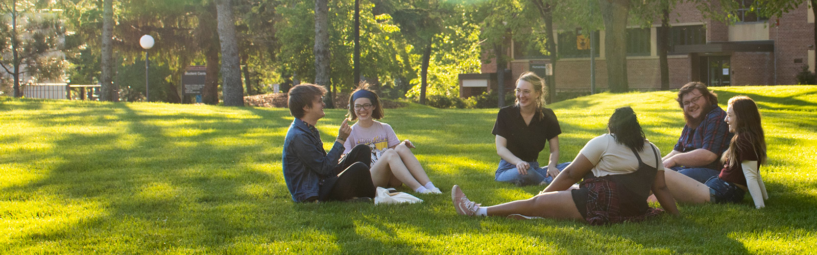A group of students sits in a circle on campus, talking together.