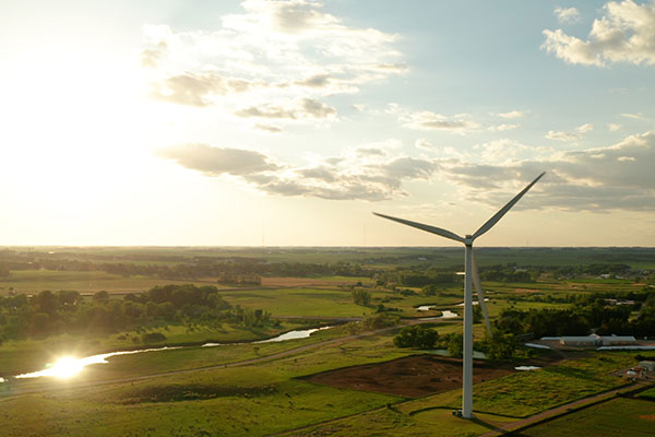 A wind turbine overlooking the Pomme de Terre River in evening sunlight.