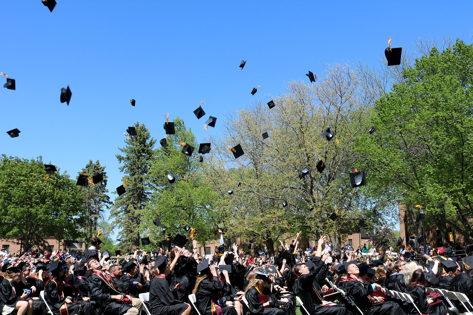 Graduates celebrate by tossing caps into the air