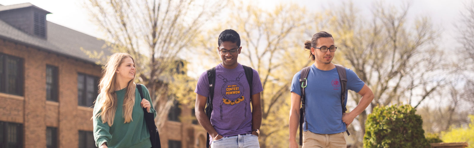 three students walk near Imholte Hall