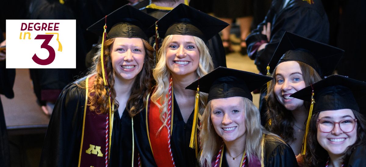 Group of student posing during graduation with a sticker of Degree in Three logo in the background. 