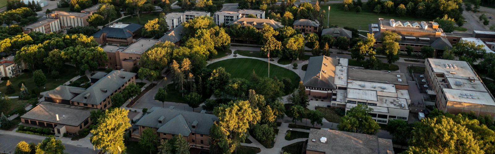 Aerial view of the University of Minnesota Morris campus surrounded by lush green trees and a central grassy mall.