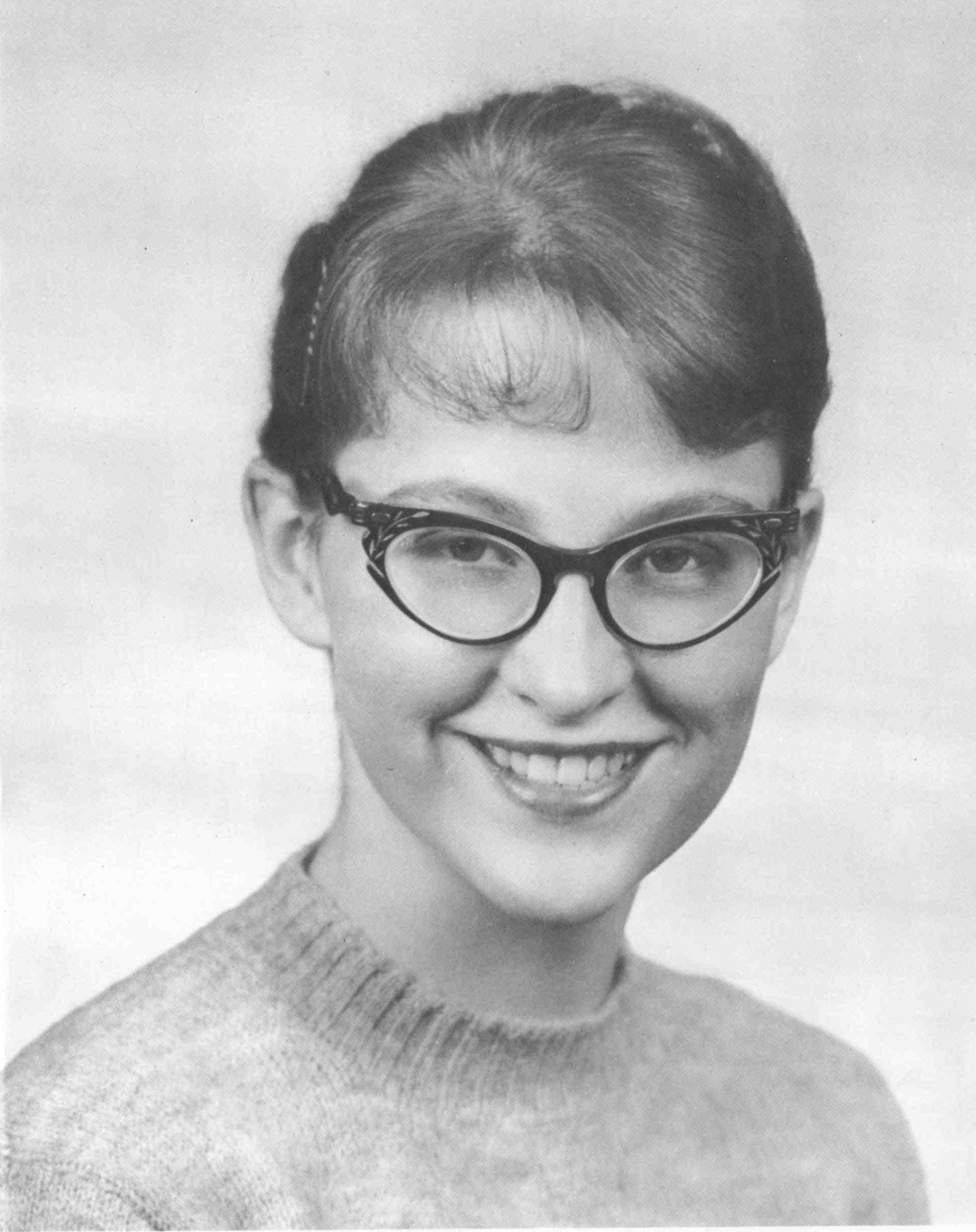 black and white photo of a young woman wearing glasses with her hair pulled back 