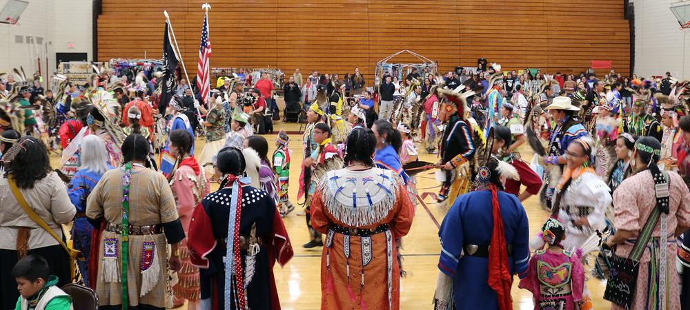 Group of people dancing at Pow Wow hosted in UMN Morris Gymnasium