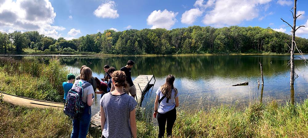 A group of students walks toward a lake at the EcoStation.