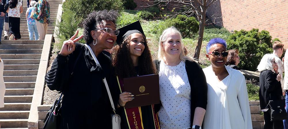 Family members pose with a graduate after commencement ceremonies on campus.