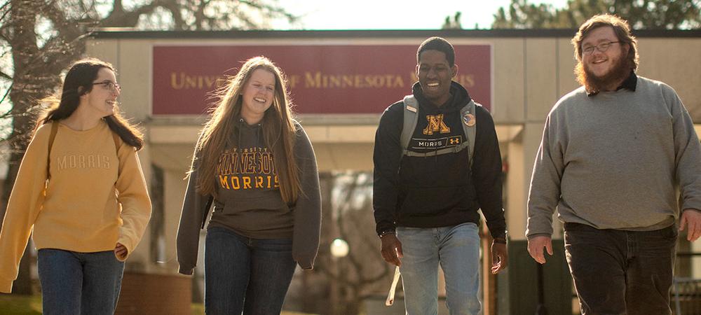 Four students walking in front of the Student Center on the UMN Morris campus.