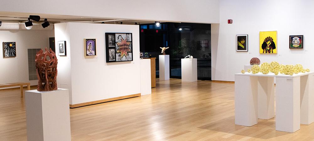Senior art exhibit on display in Morrison Gallery, an open space with white walls and natural wood floors.