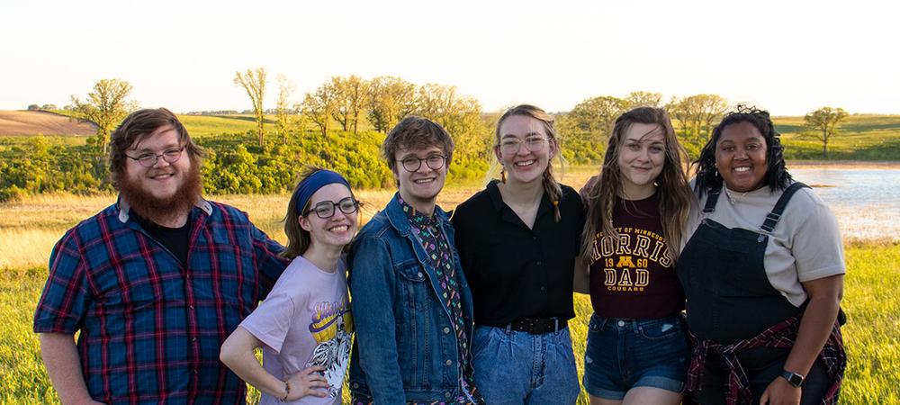 Six students stand together and smile into lens on a prairie hill near Morris.