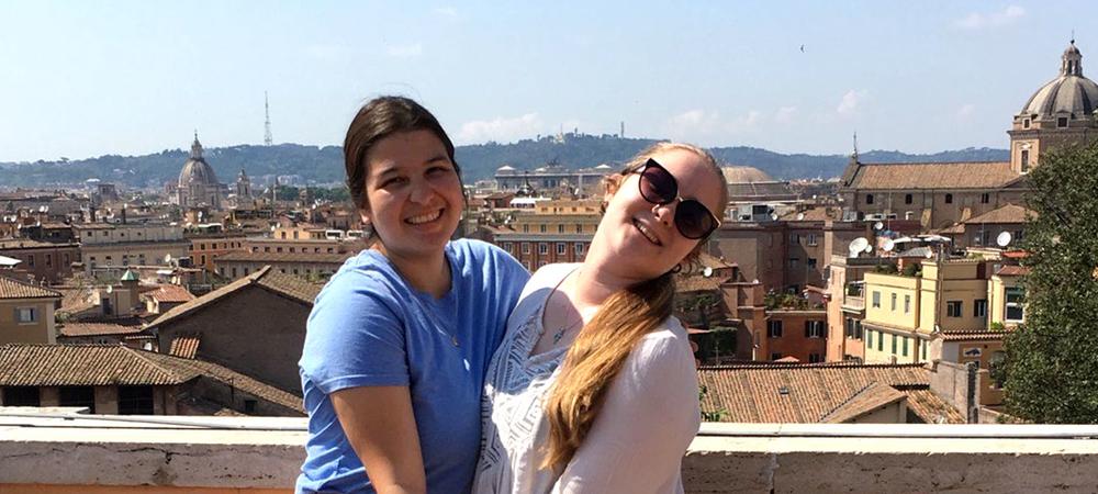 Two students posing in front of a colonial city on a study abroad trip.
