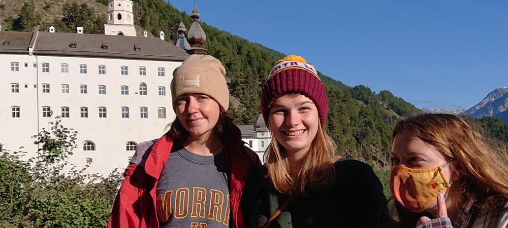 Three Morris students in the Italian Alps with a castle in the distance.