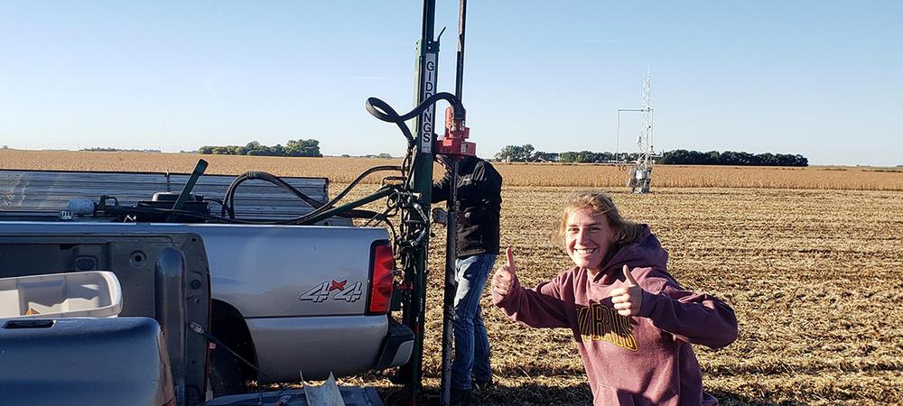 A student intern gives two thumbs up during field work.