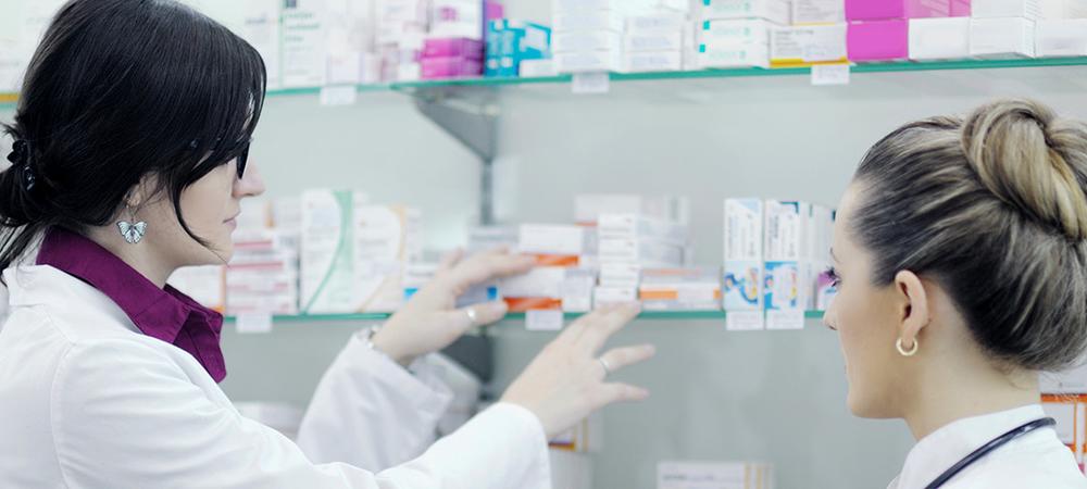 Two women in white coats work in a pharmacy