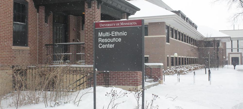 A snowy outdoor photo of two brick buildings and a sign that read, University of Minnesota Multi-Ethnic Resource Center