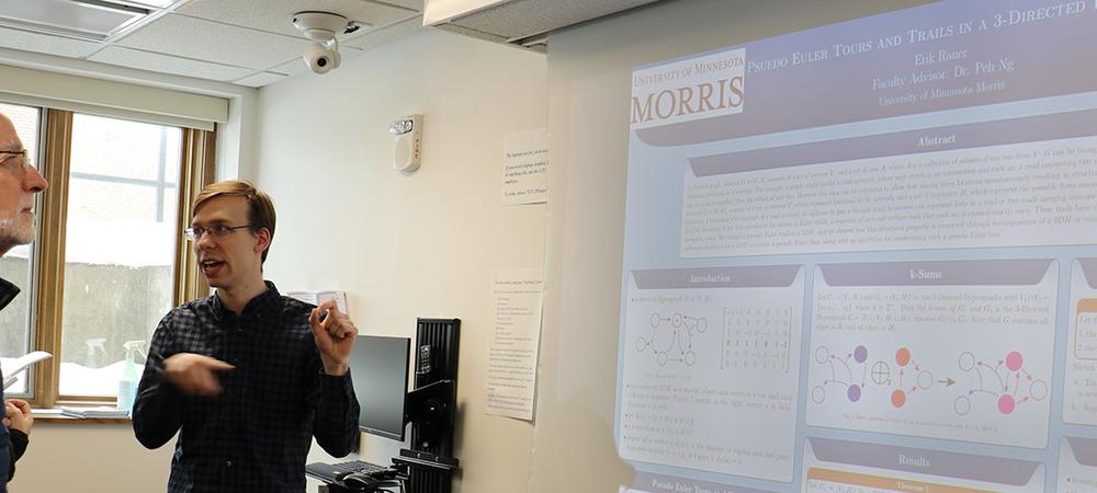 A mathematics student presents a research poster to members of the University of Minnesota Board of Regents.