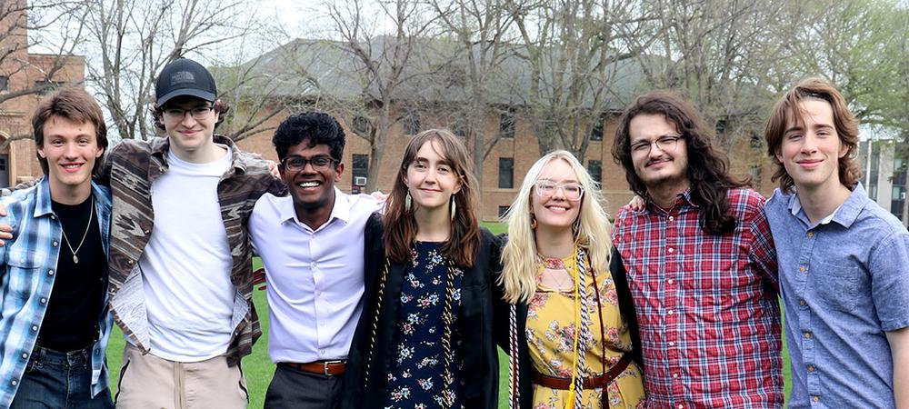 A group of philosophy majors celebrates with two graduates on the campus mall.