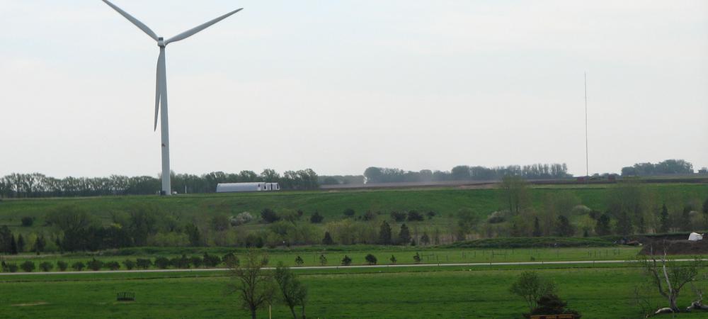 A white wind turbine in a grassy landscape
