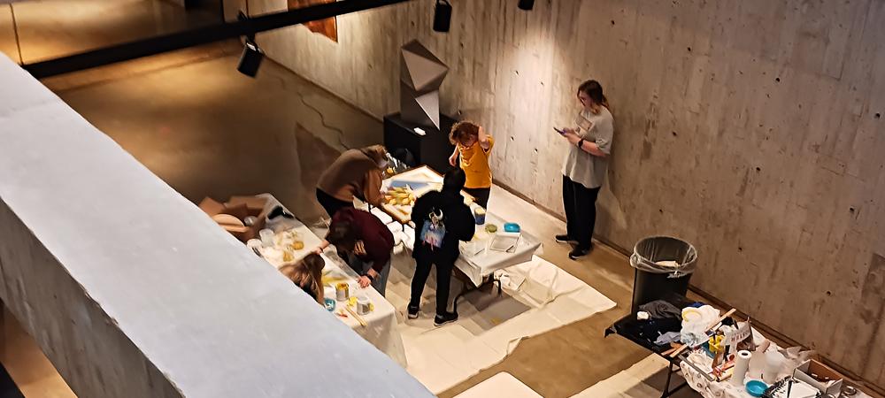 A view looking down on a group of college students painting on a table