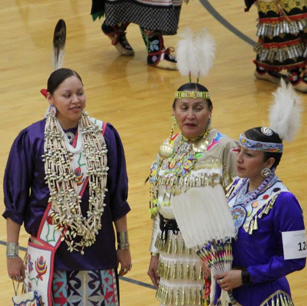 Three Native American women wearing regalia
