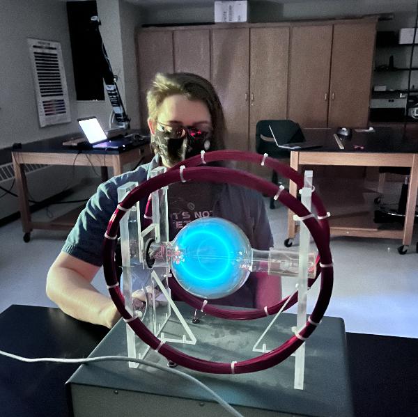 A person sitting in a physics lab with a glowing experiment