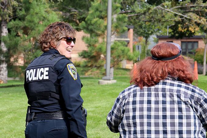 A public safety officer laughs with a student during a safety program on the campus mall.