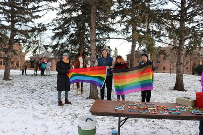 Four students holding pride flags on the campus mall