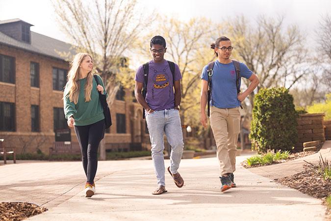 three students walk near Imholte Hall