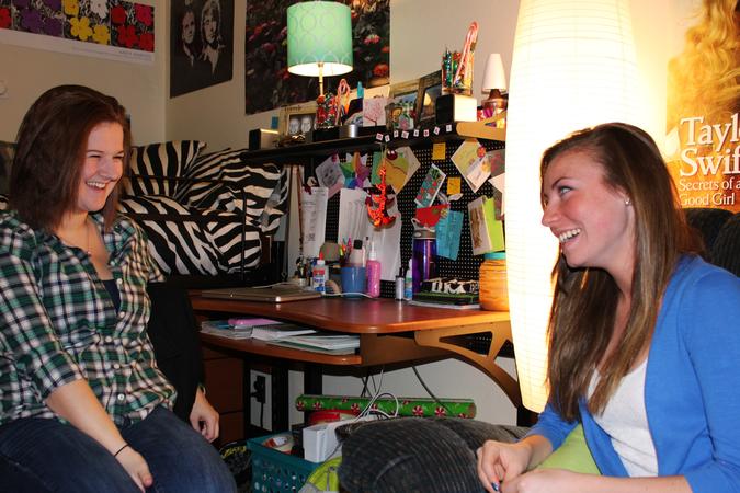 Two students talking and laughing in a residence hall room