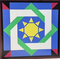 A barn quilt with a design in blue, green and yellow