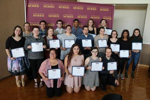 A group of 19 McNair students posing for a picture while holding certificates