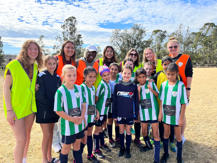 Seven college soccer players with a group of elementary-aged players.  