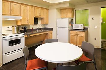 Green Prairie Community kitchen, with table, cupboards, sink, stove, refrigerator, and microwave