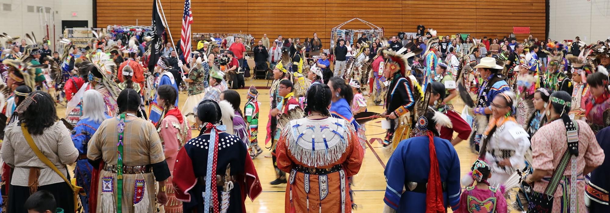 Group of people dancing at Pow Wow hosted in UMN Morris Gymnasium