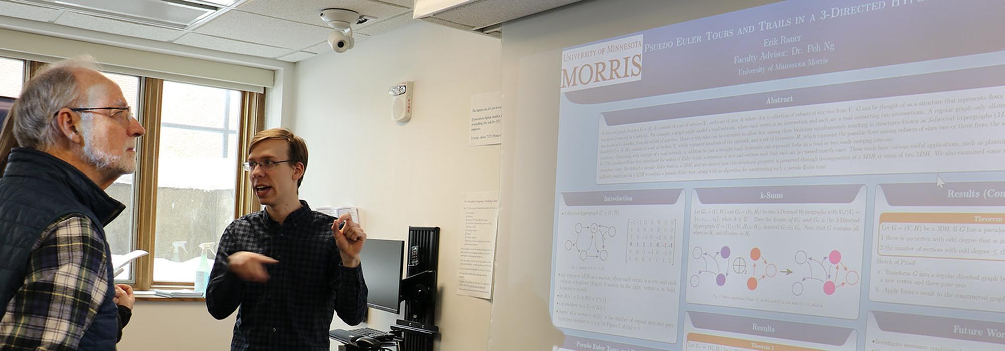 A mathematics student presents a research poster to members of the University of Minnesota Board of Regents.