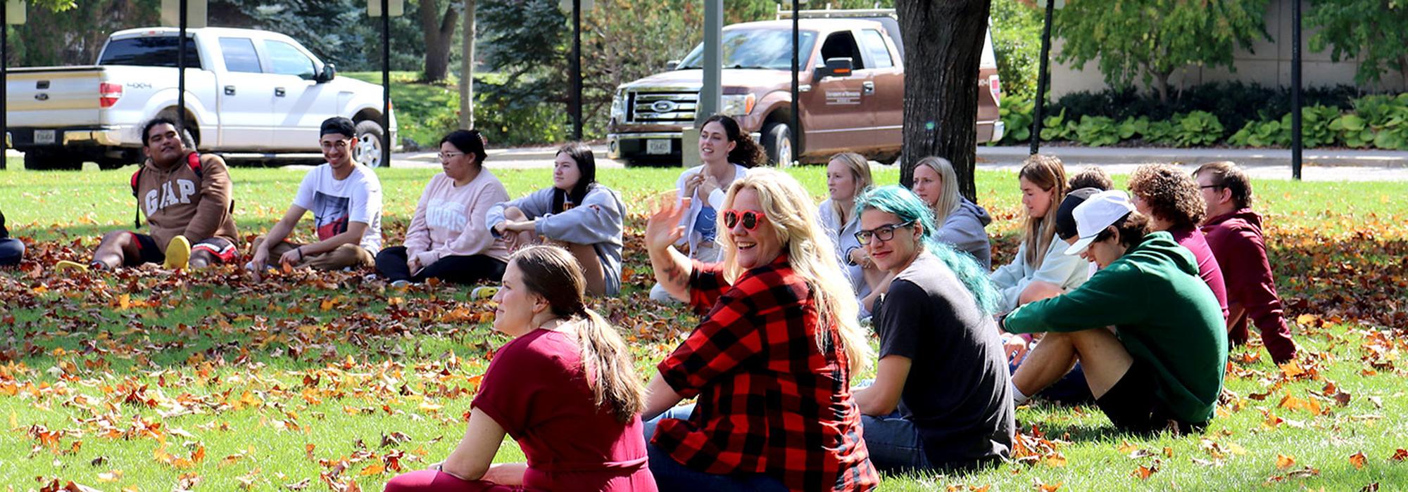 A psychology class meets outdoors on a bright fall day