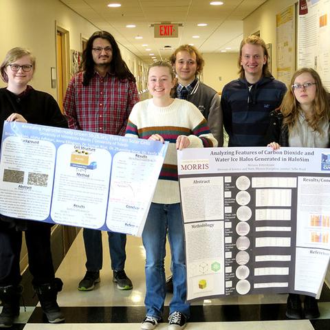 Six members of physics club pose with research posters.