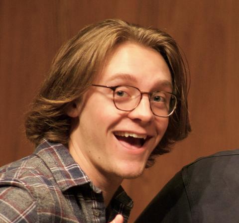 A white male with light brown hair and glasses.  He is smiling and giving a thumbs up. 