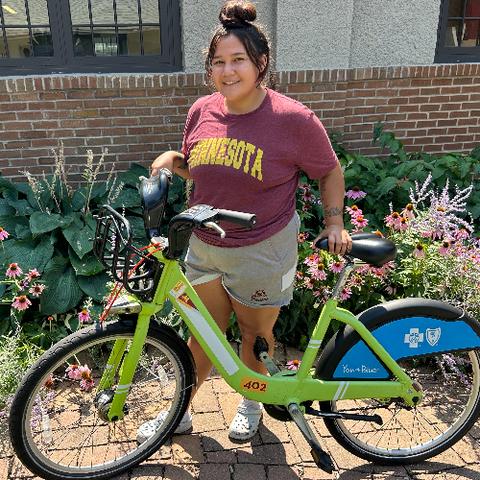 A woman wearing a Minnesota t-shirt holding a green bike