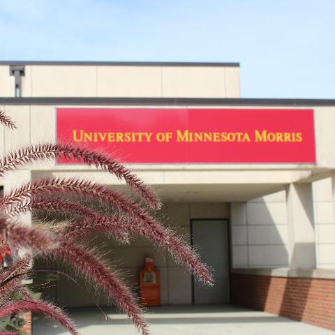 The exterior of a building with plants in front of it and a banner that reads, University of Minnesota Morris