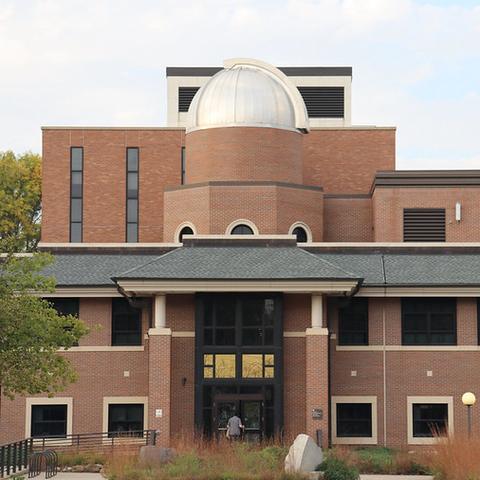The exterior of a three-story brick building with a large domed observatory 