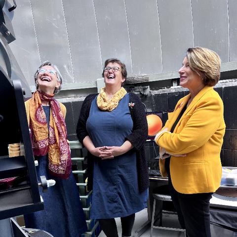 Three women standing in an observatory, looking at a telescope