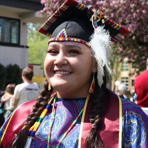 Paisley Sierra in graduation attire and Native regalia 